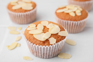 Muffins with fresh almond flakes on white table, closeup