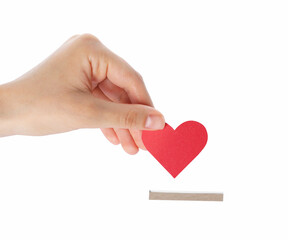 Woman putting red heart into slot of donation box against white background, closeup