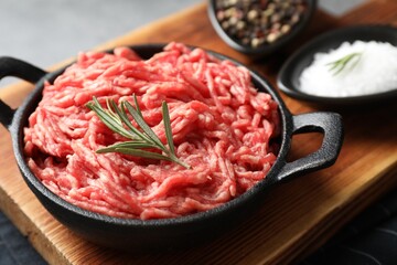 Raw ground meat in bowl and spices on table, closeup