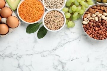 Different products and seeds high in healthy fats on white marble table, flat lay. Space for text