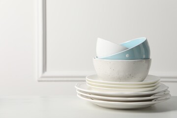 Stack of beautiful ceramic dishware on white table, space for text