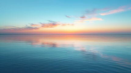 Fototapeta premium The sun dips below the horizon, creating a pastel palette of colors over a mirror-like calm sea, embodyin