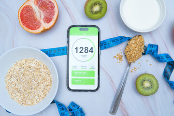 A calorie counting app displayed on a smartphone screen next to a tailor's measuring tape and a...