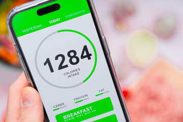 A person using a smartphone app to track calorie intake, emphasizing fitness and diet adherence