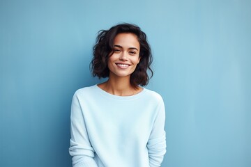 A woman with short hair is smiling and wearing a blue sweater