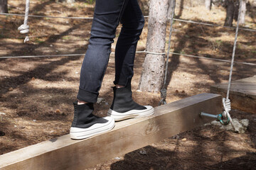 girl balancing on wooden beam in obstacle course outdoors