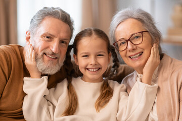 Smiling Grandparents With Their Young Granddaughter Enjoying Family Time Together