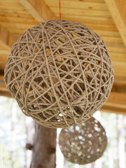 hanging spherical twine lampshade under wooden structure close up