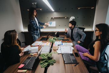 A team of four professionals engages in a lively discussion, analyzing paperwork and digital data...