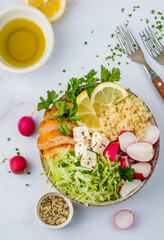 Healthy salad with bulgur, chicken breast, herbs, cabbage, radishes, feta and seeds. Top view, on a light background, close up.