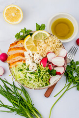 Healthy salad with bulgur, chicken breast, herbs, cabbage, radishes, feta and seeds. Top view, on a light background, close up.