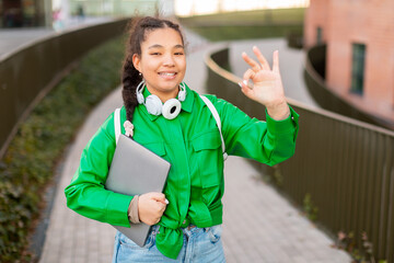 Smiling Young Girl in Green Jacket Giving Okay Gesture
