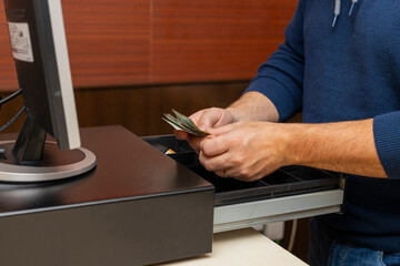 imagen de manos guardando billetes de dinero en caja registradora
