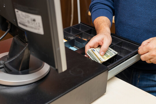 imagen de manos guardando billetes de dinero en caja registradora