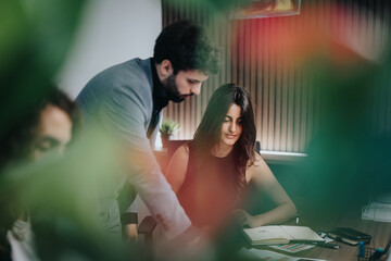 A man and a woman, depicted as business colleagues, work attentively on documents at an office. The...