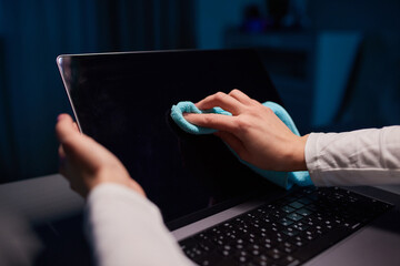 Cleaning the screen of laptop computer with microfiber cloth by hand