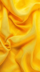 Obraz premium A yellow fabric with a pattern of waves. The fabric is folded and has a smooth texture. The color yellow is dominant in the image, giving it a warm and inviting feel