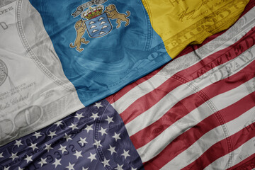 Obraz premium waving colorful flag of united states of america and national flag of canary islands on the dollar money background. finance concept.