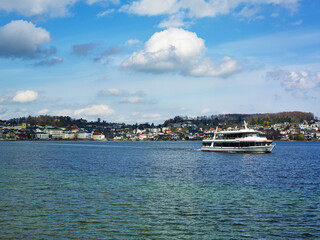 Fototapeta premium Peaceful spring mountain lake in the Alps. View of Lake Traunsee, pleasure Boat and Mount Traunstein in background. Upper Austria.