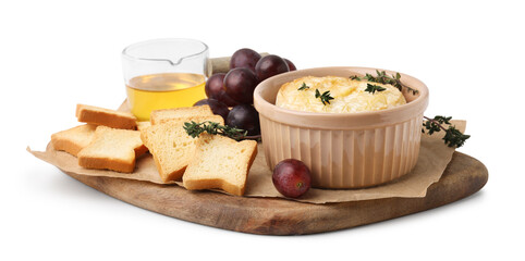 Tasty baked camembert in bowl, croutons, grapes, honey and thyme on white background