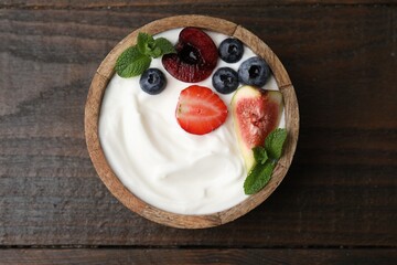 Bowl with yogurt, berries, fruits and mint on wooden table, top view