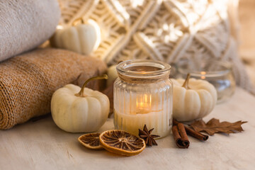 Autumn composition with aromatic candle, dry citrus, cinnamon, anise. Aromatherapy on a grey fall morning, atmosphere of cosiness and relax. Wooden background, pumpkin as decor