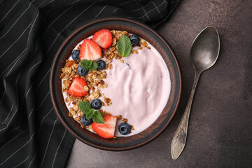 Bowl with yogurt, berries and granola on brown table, flat lay