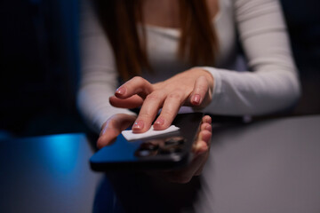 Hand female cleaning her smartphone with microfiber cloth