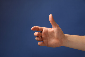 Man holding something in hand on blue background, closeup