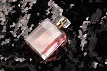 Luxury perfume in bottle on fabric with shiny sequins