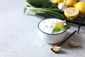 Delicious yogurt and ingredients on light textured table, space for text