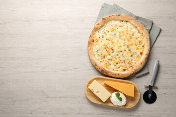 Delicious cheese pizza, cutter and different kinds of cheese on wooden table, flat lay. Space for...