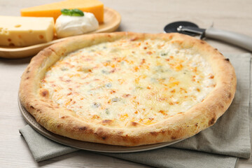Delicious cheese pizza, cutter and different kinds of cheese on wooden table, closeup