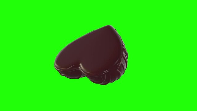 Heart shaped chocolate rotating on green background.