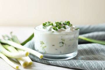 Delicious yogurt and green onion on white wooden table, closeup