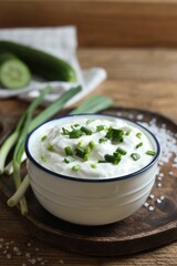 Delicious yogurt, green onion and salt on wooden table, closeup