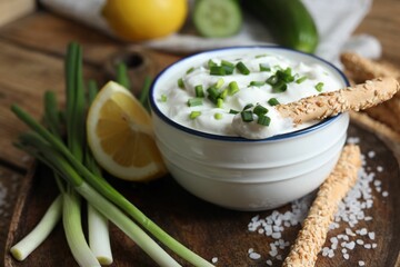 Delicious yogurt, green onion, grissini and lemon on table, closeup