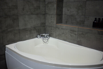 White metal whirlpool bath without water in apartment bathroom.