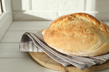 Freshly baked sourdough bread on white wooden table indoors. Space for text