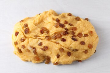 Fresh dough with raisins on white textured table, top view
