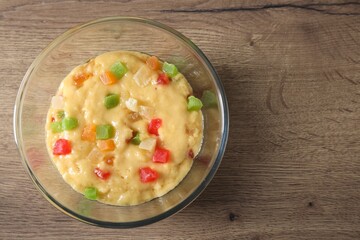 Raw dough with candied fruits in bowl on wooden table, top view. Space for text