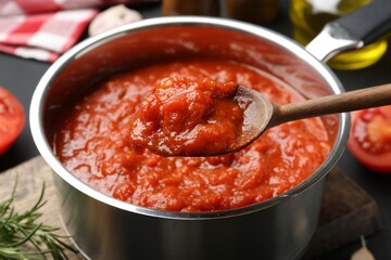 Eating homemade tomato sauce at dark table, closeup