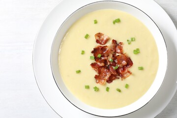 Tasty potato soup with bacon and green onion in bowl on white table, top view