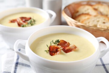 Tasty potato soup with bacon and rosemary in bowls on white table, closeup