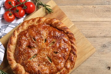 Tasty homemade pie, rosemary and tomatoes on wooden table, flat lay. Space for text