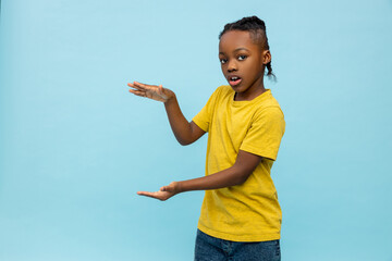 Boy in yellow tshirt standing on blue background and gesticulating