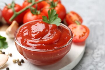 Delicious tomato ketchup and parsley in bowl on grey table, closeup