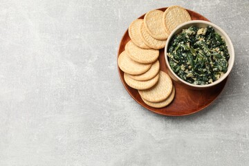 Tasty spinach dip with egg and crackers on grey table, top view. Space for text