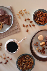 Cup of tea or coffee, cookies, macaroons, chocolate, various nuts and cocoa powder on white background. Top view.