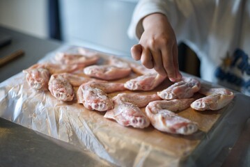 手羽先に下味を付けるのを子供が手伝っているところ